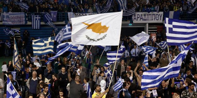 A supporter of the newly elected President of Cyprus Nicos Anastasiades waves a Cypriot flag amongst Greek ones during a proclamation ceremony at Eleftheria stadium in Nicosia February 24, 2013. Cypriot conservative leader Nicos Anastasiades won an overwhelming victory in a presidential run-off election on Sunday, boosting hopes of a swift financial rescue for the near-bankrupt island nation. REUTERS/Yorgos Karahalis (CYPRUS - Tags: POLITICS ELECTIONS)