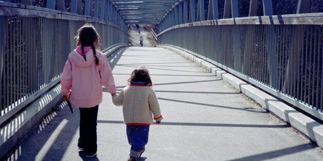 Rear view of two little girls walking on a bridge, Toronto, Canada