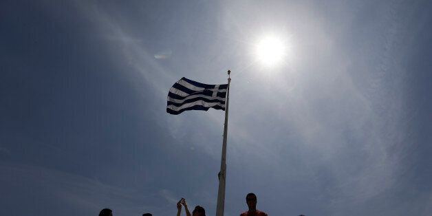 A Greek flag waves as tourists enjoy the view atop of the ancient Acropolis hill in Athens, on Monday, May 9, 2016. European finance ministers are trying to break a deadlock over whether to provide Greece with the next batch of bailout loans, which it needs to avoid bankruptcy this year, and forgive some of its debts. (AP Photo/Thanassis Stavrakis)