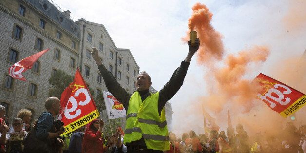 A demonstrator burns flares and shouts slogans during a demonstration in Marseille, southern France, on a day of nationwide strikes and protests over a labor reform, Thursday, May 26, 2016. French Prime Minister Manuel Valls says he is open to âimprovements and modificationsâ in a labor bill that has sparked intensifying strikes and protests, but will not abandon it. (AP Photo/Franck Pennant)