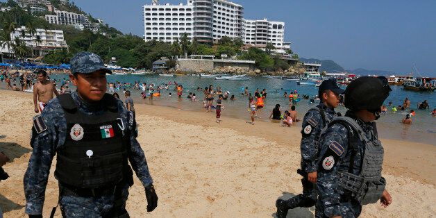 Federal police officer patrol Caleta beach crowded with local residents and tourists in Acapulco, Mexico, Friday, May 13, 2016. The city of Acapulco and Guerrero state in general have experienced a wave of violence attributed to warring drug gangs. On Saturday Mexican authorities say three men were gunned down, in a tourist-hotel quarter of the Pacific resort city. (AP Photo/Enric Marti)