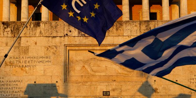 Pro-Euro demonstrators wave a Greek flag, right, and a European Union flag in front of the Tomb of the Unknown Soldier monument during a rally in Syntagma Square in Athens, in this photo dated Thursday, July 9, 2015. The latest incarnation of Greeceâs economic crisis over the span of a month saw Greece in the end accept harsh austerity measures from creditors to save the country from bankruptcy and possibly ignominiously getting kicked out of the eurozone. (AP Photo/Petros Karadjias)