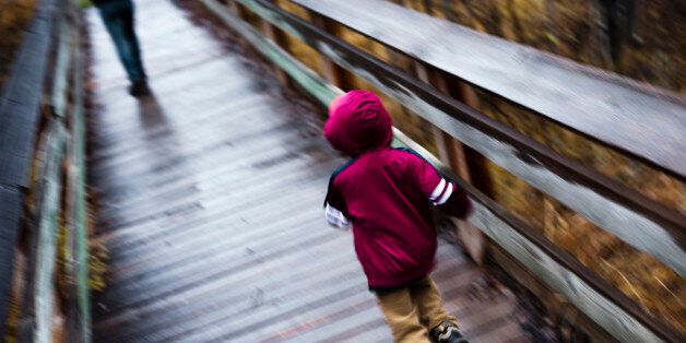 Little boy running after his mother on footbridge, blurred motion. Rock Creek, Montana.
