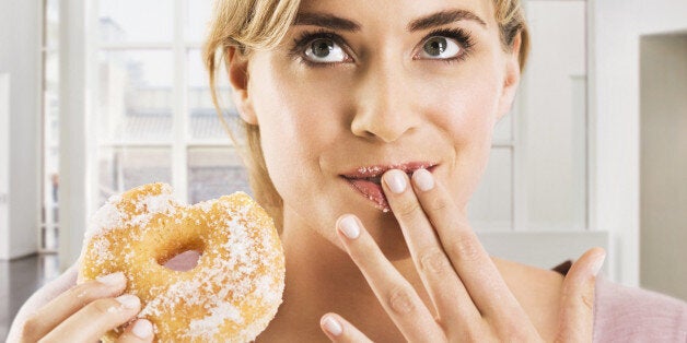 Blonde woman eating a sugar coated doughnut