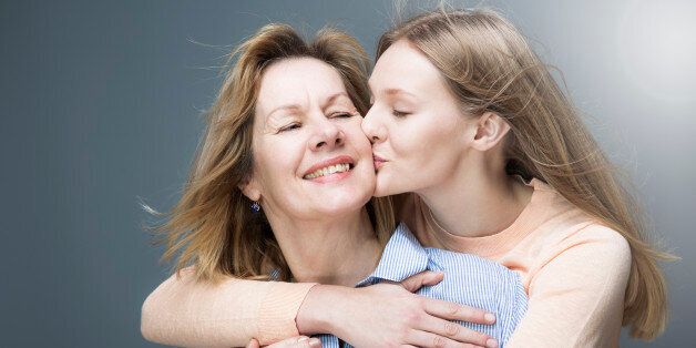 Teenage daughter kisses mother on cheek.