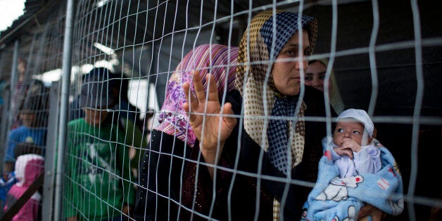 A Syrian woman holds a 9 days old baby who was born in the camp as refugees and migrants queue to receive food at the northern Greek border point of Idomeni, Greece, on Tuesday, May 10, 2016. About 54,000 refugees and migrants are currently stranded in Greece as 10,000 are camped in Idomeni, after the European Union and Turkey reached a deal designed to stem the flow of refugees into Europeâs prosperous heartland. (AP Photo/Petros Giannakouris)