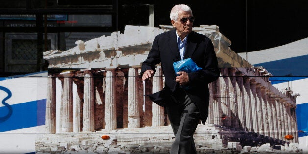 A man crosses a road in front of a bus bearing a picture of the temple of Parthenon in central Athens October 8, 2013. Greece will emerge from six years of recession next year, a draft budget forecast on Monday, signalling the country is past the worst of a crippling debt crisis that nearly broke Europe's single currency. REUTERS/John Kolesidis (GREECE - Tags: POLITICS BUSINESS SOCIETY)