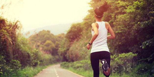 young fitness woman runner running at forest trail