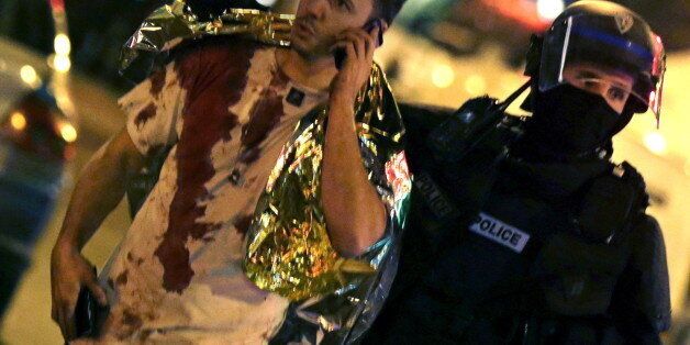 ATTENTION EDITORS - VISUAL COVERAGE OF SCENES OF INJURY A French policeman assists a blood-covered victim near the Bataclan concert hall following attacks in Paris, France, November 14, 2015. Gunmen and bombers attacked busy restaurants, bars and a concert hall at locations around Paris on Friday evening, killing dozens of people in what a shaken French President described as an unprecedented terrorist attack REUTERS/Philippe Wojazer