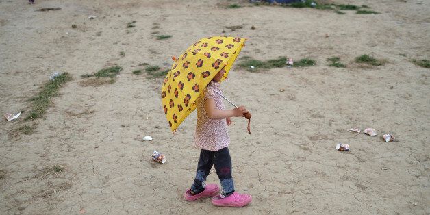 A girl holds an umbrella at a makeshift camp for migrants and refugees at the Greek-Macedonian border near the village of Idomeni, Greece, May 10, 2016. REUTERS/Marko Djurica