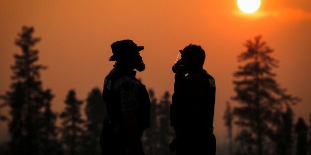 Two RCMP police officers wear gas masks in the smoke from the wildfires near Fort McMurray, Alberta, Canada, May 6, 2016. REUTERS/Mark Blinch