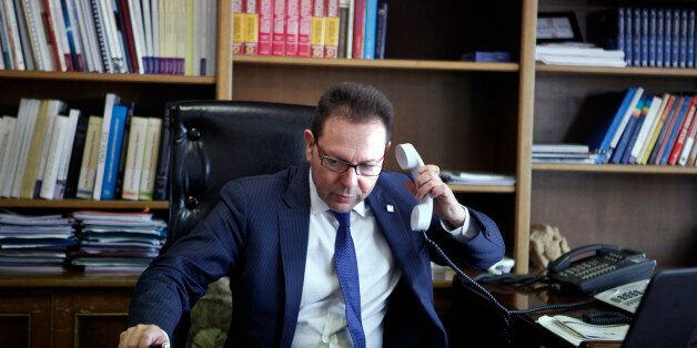 Greece's Finance Minister Yannis Stournaras picks up the phone in his office during an interview with Reuters in Athens April 2, 2014. Greece's first foray into bond markets after a four-year exclusion will be on a