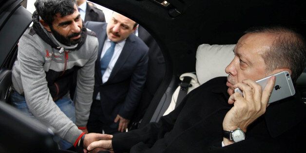 Turkish President Recep Tayyip Erdogan, right, takes Vezir Cakras by hand while speaking on his mobile phone inside his car stationed over the Bosporus Bridge in Istanbul, Friday, Dec. 25, 2015. Erdoganâs office says the Turkish president has talked Cakras out of jumping off a bridge to commit suicide. Television footage on Friday showed Erdoganâs motorcade stopping over Istanbulâs Bosporus Bridge where a man was apparently contemplating jumping off. An official from Erdoganâ