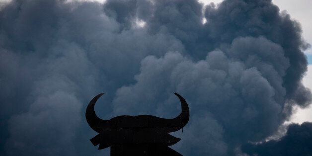 The shape of an 'Osborne Bull' is pictured with black clouds of smoke on the background, produced by tyres burning in an uncontrolled dump near the town of Sesena, after a fire brokeout early on May 13, 2016.A huge waste ground near Madrid where millions of tyres have been dumped was on fire today, releasing a thick black cloud of toxic fumes that officials worry could harm residents nearby. / AFP / PEDRO ARMESTRE (Photo credit should read PEDRO ARMESTRE/AFP/Getty Images)