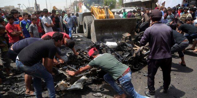 Civilians help a municipality bulldozer cleans up while citizens inspect the scene after a car bomb explosion at a crowded outdoor market in the Iraqi capital's eastern district of Sadr City, Iraq, Wednesday, May 11, 2016. An explosives-laden car bomb ripped through a commercial area in a predominantly Shiite neighborhood of Baghdad on Wednesday, killing and wounding dozens of civilians, a police official said. (AP Photo/ Khalid Mohammed)