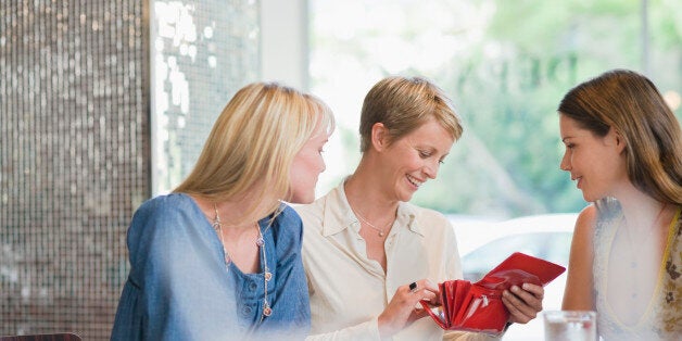 Woman sitting with her friends in a restaurant and looking into her wallet