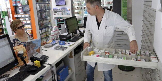 A pharmacist (R) searches for medicine for a client at a pharmacy at the city of Iraklio in the island of Crete, Greece July 7, 2015. Greece has enough medicine to last three to four months and drugmakers said on Monday that they would continue supplying the country for now, despite increased financial uncertainty after Greeks rejected austerity terms of a bailout. REUTERS/Stefanos Rapanis