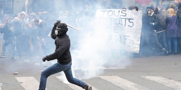 Youth throws a stick on riot police officers during a protest in Paris, Tuesday, May 17, 2016. Truckers blocked French highways and workers marched through city streets Tuesday to protest longer working hours, but President Francois Hollande is insisting he won't abandon the labor reforms that sparked their anger. (AP Photo/Francois Mori)