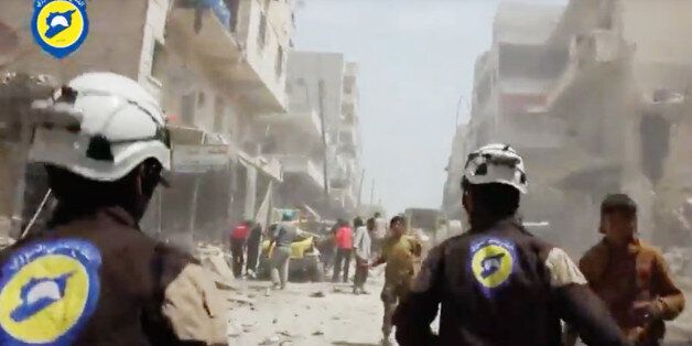 In this image made from video posted online by the Syrian Civil Defense White Helmets, Civil Defense workers run after airstrikes and shelling hit Aleppo, Syria, Sunday, April 24, 2016. Air strikes and shelling pounded Aleppo for a third straight day Sunday, killing two young siblings and more than a dozen others in Syria's largest city and former commercial capital. (Syrian Civil Defense White Helmets via AP video)