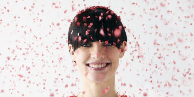 woman smiling with red confetti falling on head