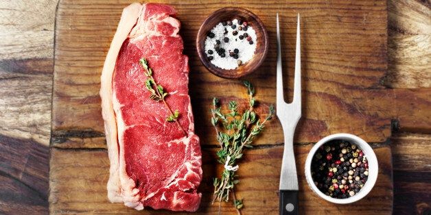 Raw beef steak with spices and herbs on wooden background