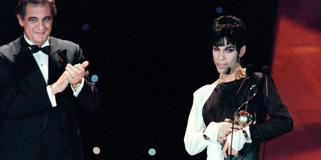 This photo taken on May 4, 1994 shows musician Prince (R) acknowledging applause after receiving from Italian tenor Placido Domingo (L) the 'Outstanding Contribution to the Pop Industry' award during the World Music Awards ceremony in Monaco.Pop icon Prince -- whose pioneering brand of danceable funk made him one of music's most influential figures -- died on April 21, 2016 at his compound in Minnesota. He was 57. The announcement came just a week after the Grammy and Oscar winner was taken to hospital with a bad bout of influenza, although he made light of his health problems after the scare. / AFP / Patrick HERTZOG (Photo credit should read PATRICK HERTZOG/AFP/Getty Images)