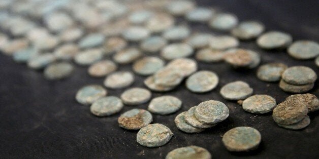 Pablo Betzer, the Israel Antiquities Authority (IAA) district archaeologist for Judah, displays newly-discovered 2000-year-old coins, dating back to the Great Revolt of the Jews against the Romans in the first century A.D., on August 5, 2014, at the IAA office in Jerusalem. The hoard, which was kept in a ceramic money box, was found during excavation near the highway between Jerusalem and Tel Aviv, including 114 bronze coins from the same period. AFP PHOTO/GALI TIBBON (Photo credit should read GALI TIBBON/AFP/Getty Images)