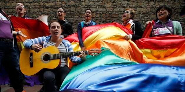 Activists sing as they wait outside a local court where Carlos Hernando and Gonzalo Ruiz were the first same-sex couple in Colombia to be joined in a civil union, in Bogota, Colombia, Wednesday, July 24, 2013. (AP Photo/Fernando Vergara)