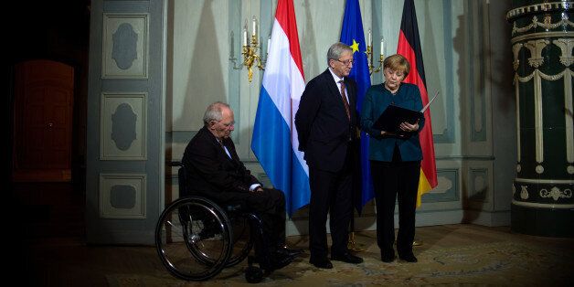 German Chancellor Angela Merkel (R) and German Finance Minister Wolfgang Schaueble (L) present Luxembourg Prime Minister Jean-Claude Juncker with the Order of Merit of the Federal Republic of Germany at the German government's guesthouse at Meseberg, outside Berlin on November 8, 2013. Juncker was awarded the Order of Merit of the Federal Republic of Germany for his outstanding commitment to the European project. AFP PHOTO / POOL / JOHANNES EISELE (Photo credit should read JOHANNES EISELE/AFP/Getty Images)