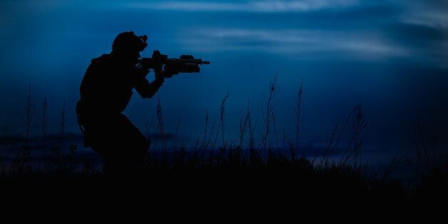 Silhouette of military soldier or officer with weapons at night. shot, holding gun, blue colorful sky, background