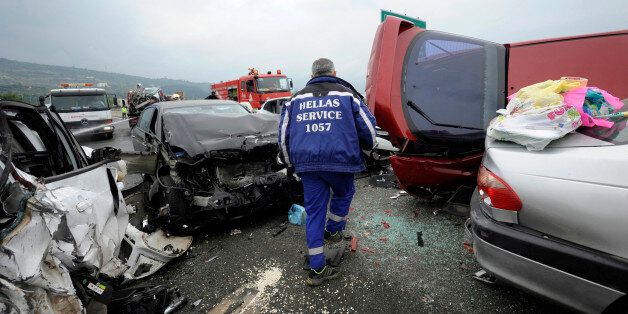 A worker from a road assistance company walks through destroyed cars following a massive car accident on a motorway in northern Greece October 5, 2014. Greek media reported that a truck caused a pile-up with dozens of cars in which four people were killed and at least 20 were injured on Egnatia motorway a few kilometres off Thessaloniki. REUTERS/Alexandros Avramidis (GREECE - Tags: SOCIETY DISASTER TRANSPORT TPX IMAGES OF THE DAY)