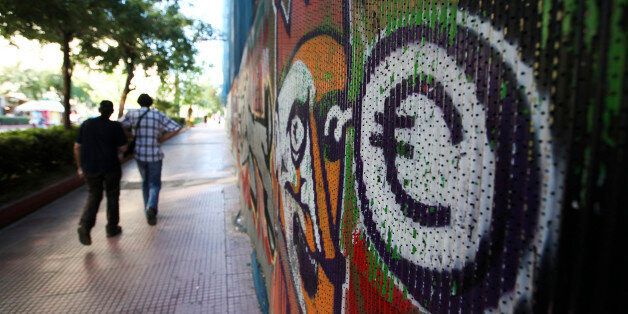 Pedestrians pass a graffiti artwork showing a euro symbol on a street in Athens, Greece, on Thursday, June 21, 2012. Lenders of 240 billion euros ($301 billion) to Greece offered no sign of granting extra time for the newly installed Athens government to meet deficit-cut targets. Photographer: Chris Ratcliffe/Bloomberg via Getty Images