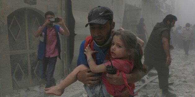ALEPPO, SYRIA - APRIL 29: (EDITORS NOTE: Image depicts graphic content.) Man carries an injured child after regime helicopters target a medical center at opposition controlled Bustan el Kasr region of Aleppo, Syria on April 29, 2016. (Photo by Beha el Halebi/Anadolu Agency/Getty Images)