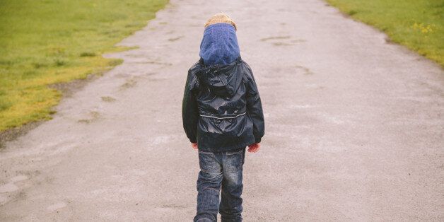 Little boy walking down a country road in the Lake District on a rainy day