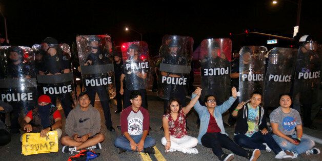 Demonstrators sit in front of a line of police in riot gear outside Republican U.S. presidential candidate Donald Trump's campaign rally in Costa Mesa, California April 28, 2016. REUTERS/Mike Blake