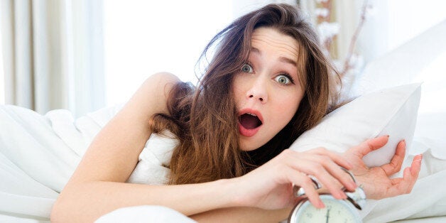 Shocked young woman waking up with alarm