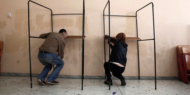 Municipal workers assemble voting booths at a voting center in Athens, Friday, Jan. 23, 2015. Prime Minister Antonis Samaras' New Democracy party has failed so far to overcome a gap in opinion polls with the anti-bailout Syriza party ahead of the Jan. 25 general election. (AP Photo/Petros Giannakouris)