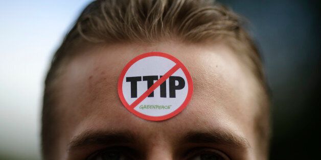 A man has a sticker by the environment organization Greenpeace against TIPP on his forehead during a protest against the planned Transatlantic Trade and Investment Partnership, TTIP, and the Comprehensive Economic and Trade Agreement, CETA, ahead of the visit of United States President Barack Obama in Hannover, Germany, Saturday, April 23, 2016. (AP Photo/Markus Schreiber)
