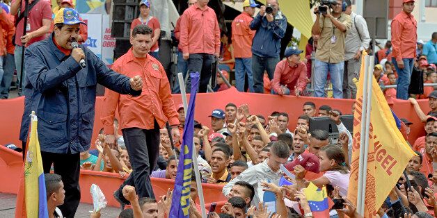 Venezuelan president Nicolas Maduro (L) greets supporters during a march to mark International Workers' Day, in Caracas on May 1, 2016. / AFP / JUAN BARRETO (Photo credit should read JUAN BARRETO/AFP/Getty Images)