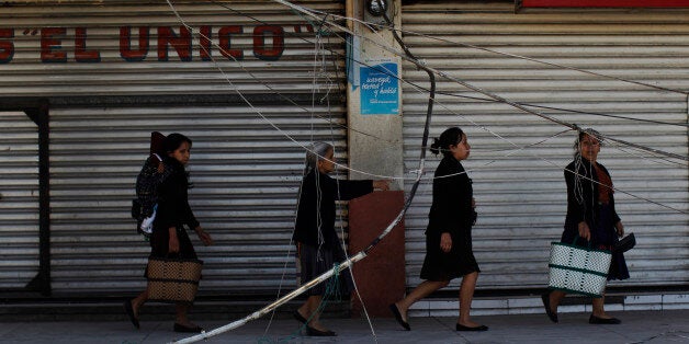 Women walk past a damaged wall of the central market in San Pedro, in the northwest region of San Marcos, Guatemala July 8, 2014. A strong earthquake shook the border between Guatemala and Mexico on Monday, killing at least three people, including a newborn boy, damaging dozens of buildings and triggering landslides. Much of the damage from the 6.9-magnitude quake was reported in the Guatemalan border region of San Marcos, where it downed power lines, cracked buildings and triggered landslides that blocked roads. REUTERS/Jorge Dan Lopez (GUATEMALA - Tags: DISASTER ENVIRONMENT)