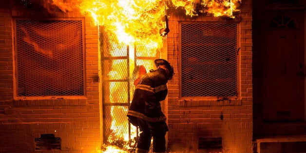 A firefighter uses a saw to open a metal gate while fighting a fire in a convenience store and residence during clashes after the funeral of Freddie Gray in Baltimore, Maryland in the early morning hours of April 28, 2015. Baltimore erupted in violence as hundreds of rioters looted stores, burned buildings and injured at least 15 police officers following the funeral of Gray, a 25-year-old black man who died after he was injured in police custody. REUTERS/Eric Thayer TPX IMAGES OF THE DAY