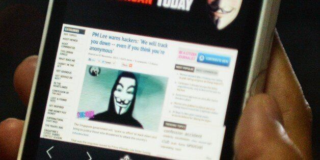 Activist hacker group Anonymous is seen through the internet government website of Singapore Prime Minister Office circulated online on a smartphone in Singapore on November 7, 2013. Singapore Prime Minister Lee Hsien Loong's official website was briefly hacked November 7, by apparent members of activist group Anonymous after he vowed to hunt down anyone who attacks the city-state's technology network. AFP PHOTO/ROSLAN RAHMAN (Photo credit should read ROSLAN RAHMAN/AFP/Getty Images)