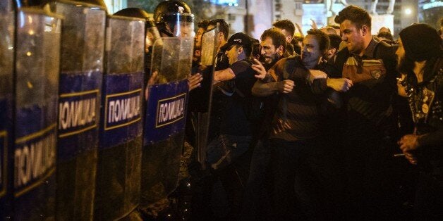 Protesters clash with anti-riot police officers in Skopje on April 13, 2016 during a protest to demand the resignation of President Gjorge Ivanov over his decision to block judicial proceedings against top politicians embroiled in a wire tapping scandal. Protesters broke into the offices of Macedonia's presidency and set fire to the furniture in sporadic clashes in the capital Skopje, as thousands took to the streets in an anti-government protest. Demonstrators were pelting several buildings wit