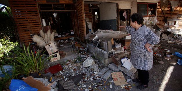 A local resident cleans up her house in Mashiki, Kumamoto prefecture, southern Japan, Friday, April 15, 2016. Aftershocks rattled communities in southern Japan as businesses and residents got a fuller look Friday at the widespread damage from an unusually strong overnight earthquake. (AP Photo/Koji Ueda)