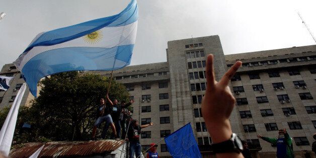 Supporters of former Argentine President Cristina Fernandez de Kirchner wave an Argentine national flag outside a Justice building where she attended court to answer questions over a probe into the sale of U.S. dollar futures contracts at below-market rates by the central bank during her administration, in Buenos Aires, Argentina, April 13, 2016. REUTERS/Martin Acosta