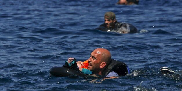 A Syrian refugee holding a baby in a life tube swims towards the shore after their dinghy deflated some 100m away before reaching the Greek island of Lesbos, September 13, 2015. Reuters and The New York Times shared the Pulitzer Prize for breaking news photography for images of the migrant crisis in Europe and the Middle East. REUTERS/Alkis Konstantinidis TPX IMAGES OF THE DAY