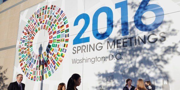 People are seen in front of a banner during the 2016 International Monetary Fund, World Bank Spring Meetings at IMF headquarters on April 14, 2016. / AFP / MANDEL NGAN (Photo credit should read MANDEL NGAN/AFP/Getty Images)