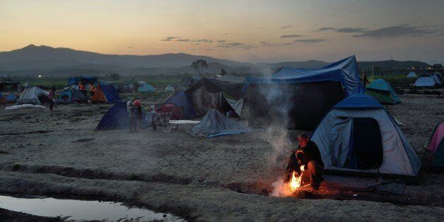 A man sits by a fire at a makeshift camp set by migrants and refugees at the Greek-Macedonian border near the village of Idomeni, on April 17, 2016.According to statistics released on on April 8 by the International Organization of Migrants (IOM), more than 152,000 people have arrived in Greece by sea from Turkey since January 1, nearly three-quarters of whom were Syrians. / AFP / DANIEL MIHAILESCU (Photo credit should read DANIEL MIHAILESCU/AFP/Getty Images)