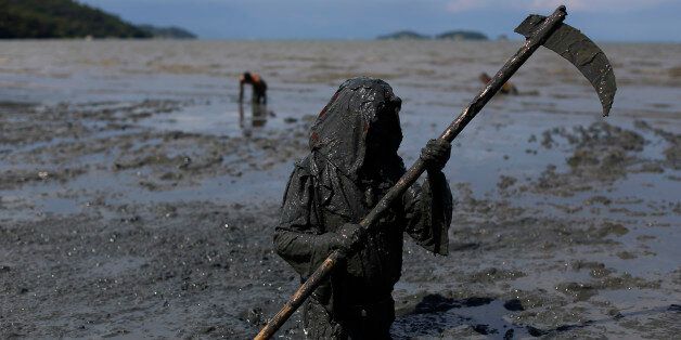 A mud covered reveler wearing a grim reaper costume enjoys the traditional