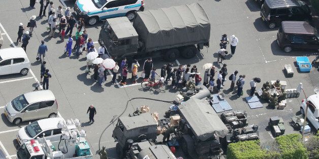 An aerial view shows residents forming a queue to receive meals from defense forces soldiers at the Mashiki town hall in Kumamoto prefecture, on April 15, 2016, after a strong 6.4-magnitude earthquake hit Japan's southwestern island of Kyushu the day before.Rescuers were rifling through the remains of collapsed building in southern Japan on April 15, after a powerful earthquake left at least nine people dead and injured hundreds, sparking fires and buckling roads. / AFP / JIJI PRESS / JIJI PRESS / Japan OUT (Photo credit should read JIJI PRESS/AFP/Getty Images)